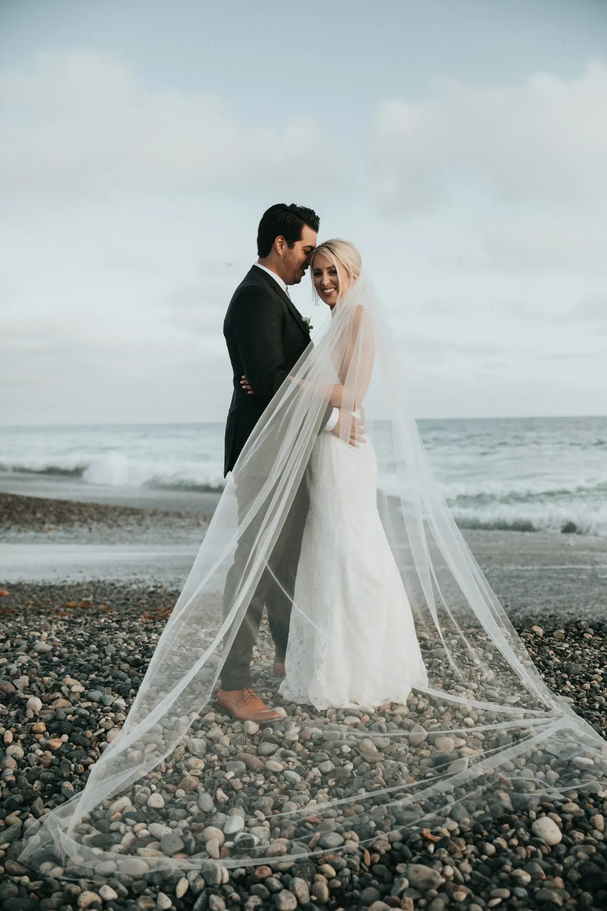 Bride and groom with a long veil on the beach
