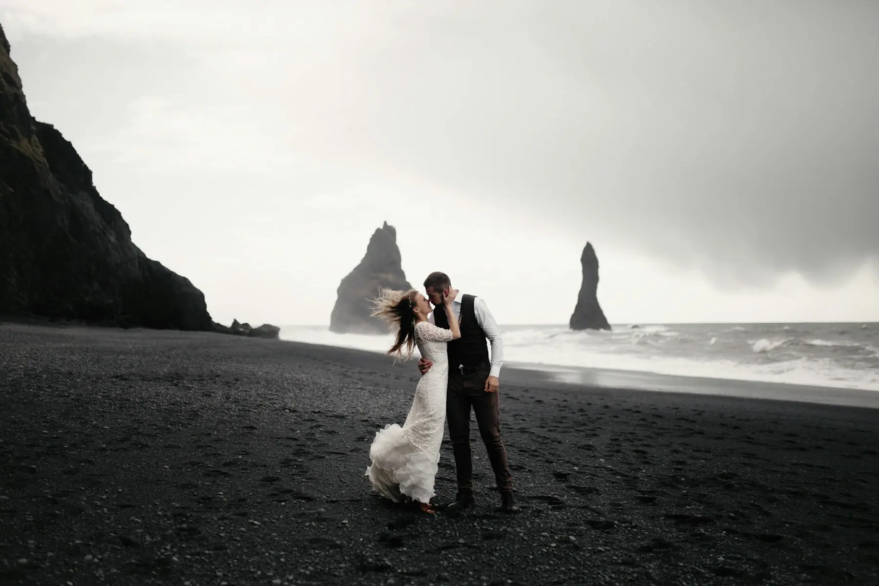Bride and groom embracing on a black sand beach