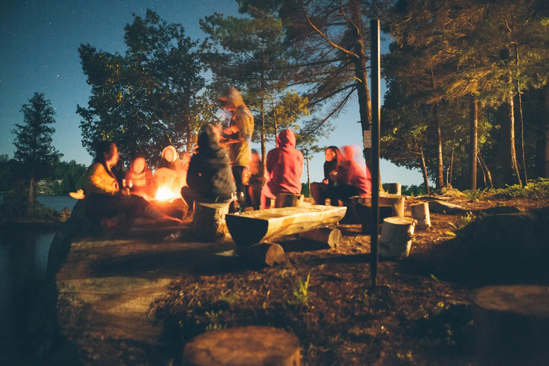 Friends gathered around a campfire at dusk