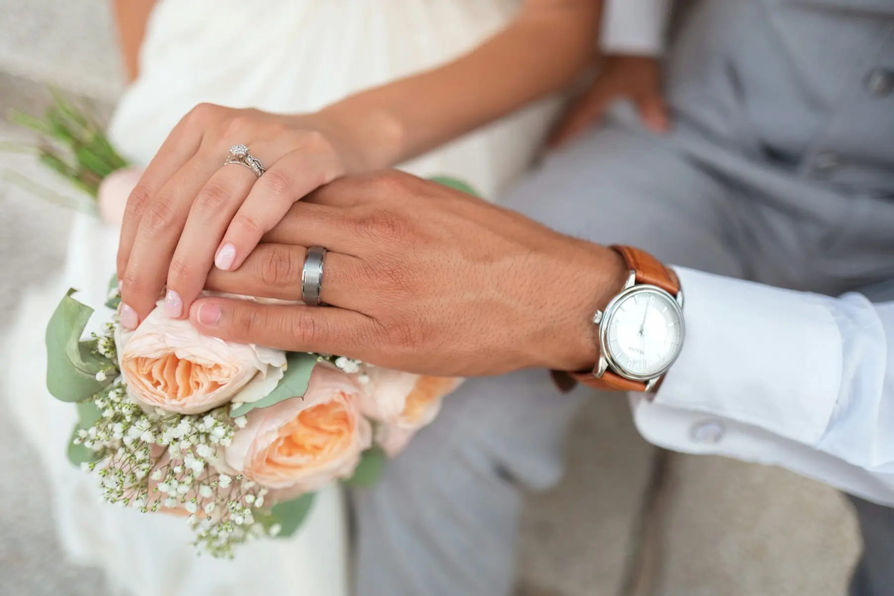 Newlyweds holding hands over a bouquet