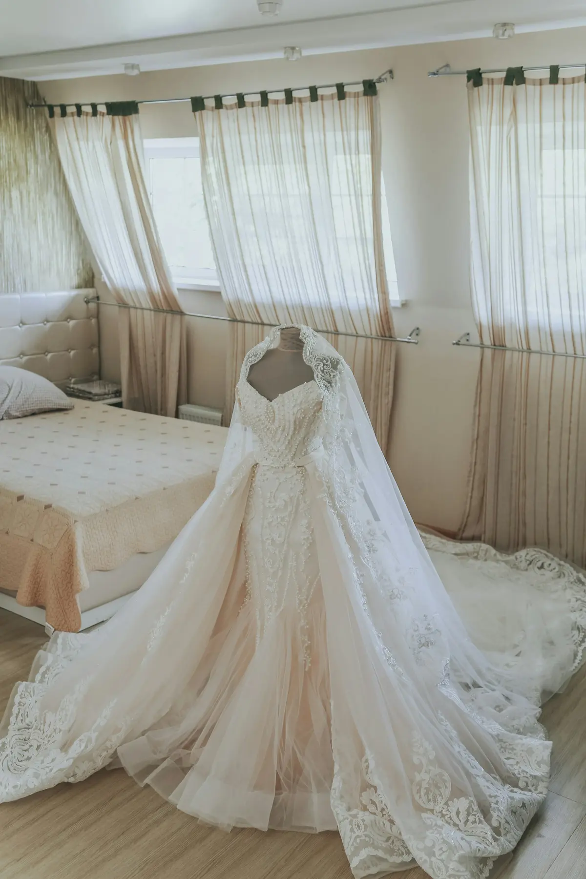 Wedding gown hanging on a dress form by a sunny window